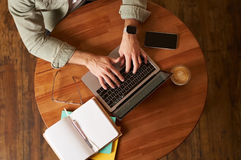 cropped-top-view-male-hands-man-typing-laptop-keyboard-working-cafe-sitting-round-table (1)